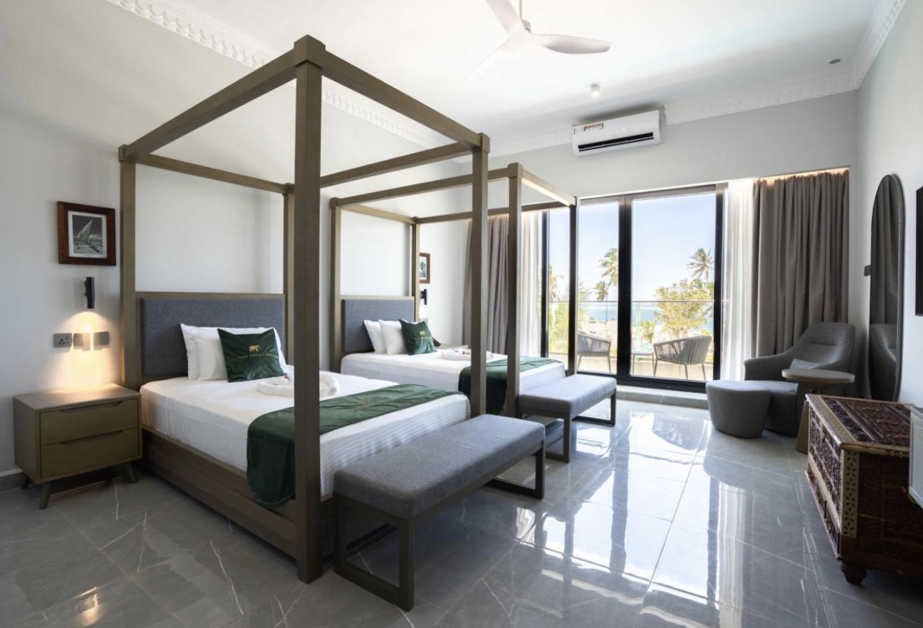 Guest room with four-poster beds and ocean-view balcony
